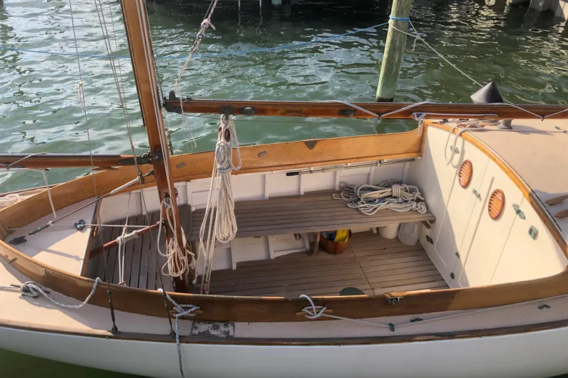 Slide: The Image of 1974 Herreshoff Rozinante sailboat with wooden deck and rigging, docked on calm water. - 16