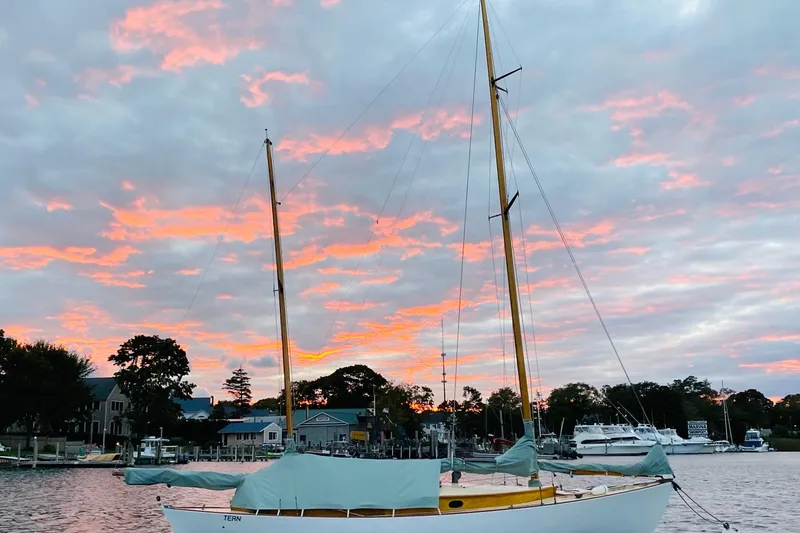 Slide: The Image of 1974 Herreshoff Rozinante sailboat at sunset with vibrant sky and waterfront view. - 44