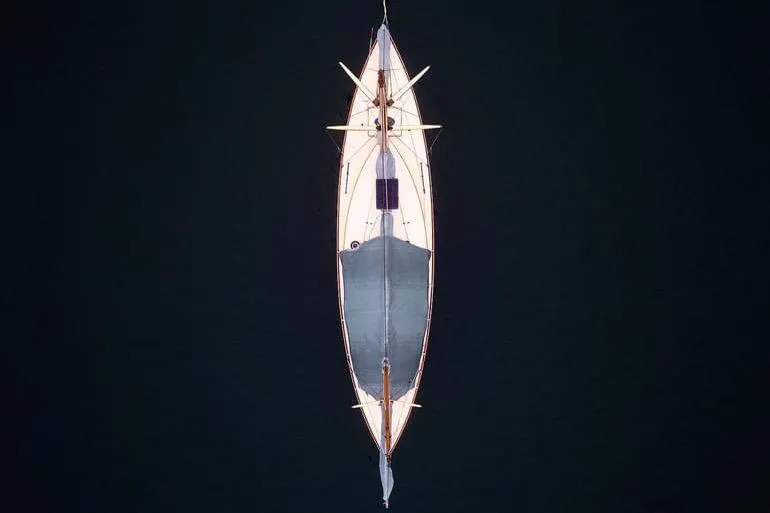 Slide: The Image of Aerial view of 1974 Herreshoff Rozinante sailboat on dark water. - 62