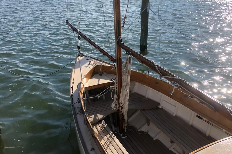 Slide: The Image of 1974 Herreshoff Rozinante sailboat docked on shimmering water. - 17