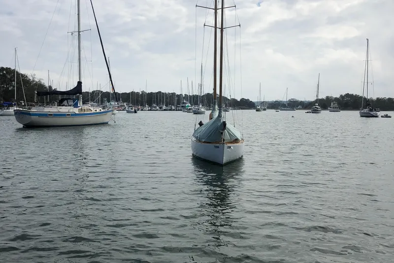 Slide: The Image of 1974 Herreshoff Rozinante sailboat moored in a calm marina with other boats. - 50