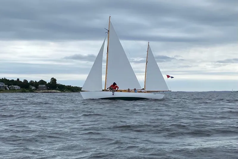 Slide: The Image of 1974 Herreshoff Rozinante sailboat on open water under cloudy skies. - 10