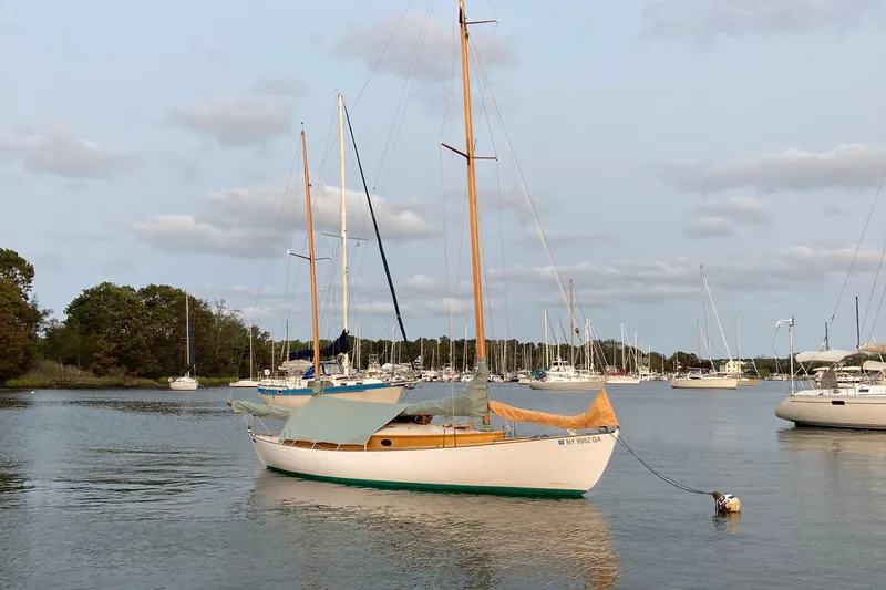 Slide: The Image of 1974 Herreshoff Rozinante sailboat moored in a tranquil marina setting. - 43