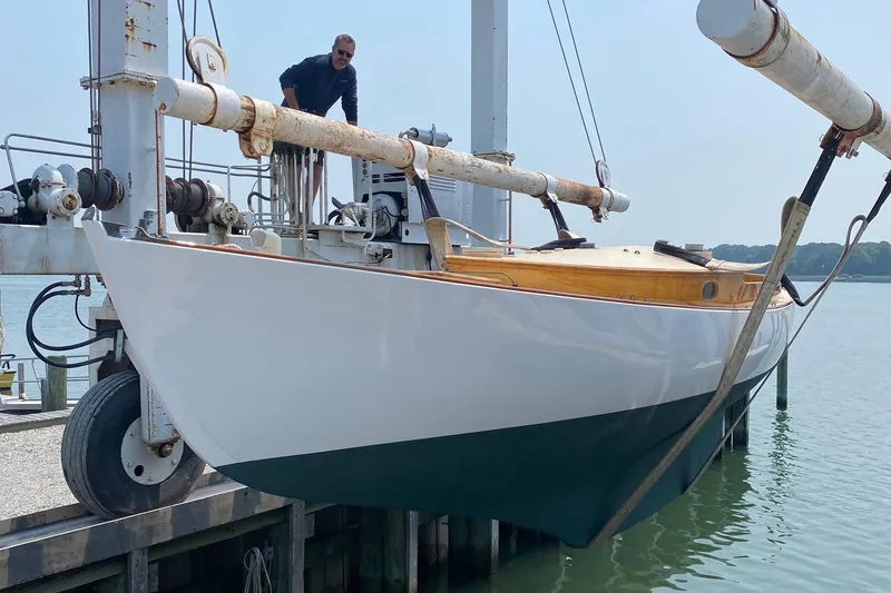 Slide: The Image of 1974 Herreshoff Rozinante sailboat on a lift, with a person inspecting it. - 23