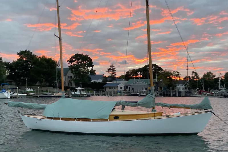 Slide: The Image of 1974 Herreshoff Rozinante sailboat at sunset, docked near waterfront homes. - 41