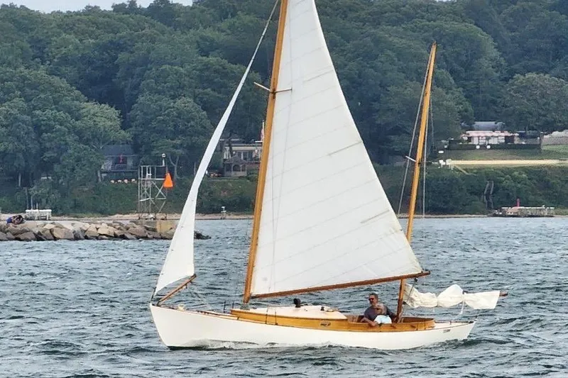 Slide: The Image of 1974 Herreshoff Rozinante sailboat on water, surrounded by lush greenery. - 6