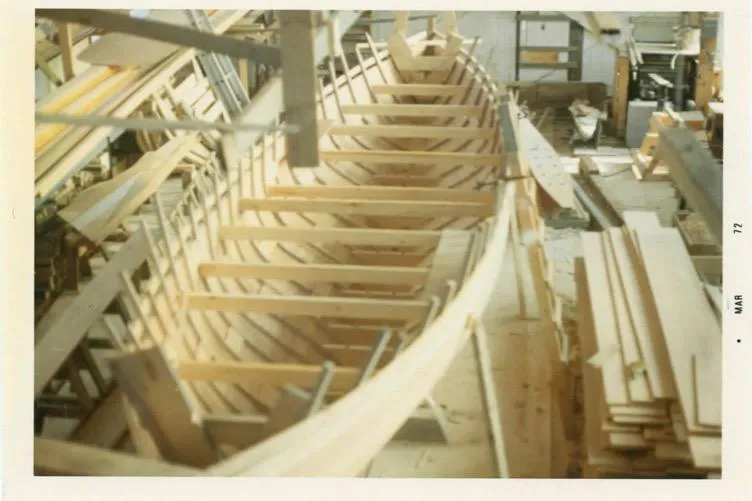 Slide: The Image of 1974 Herreshoff Rozinante boat under construction in a workshop, showcasing wooden framework. - 65