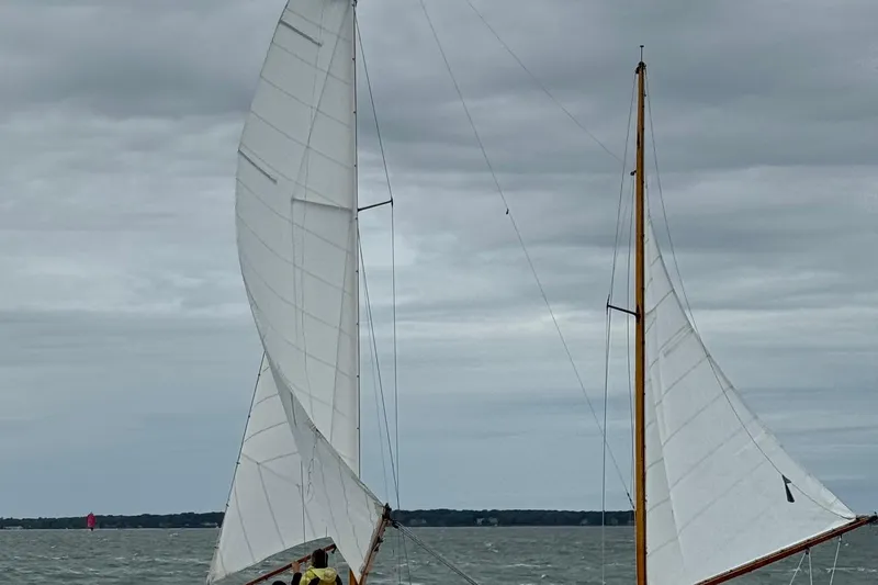 Slide: The Image of 1974 Herreshoff Rozinante sailboat with white sails on a cloudy day at sea. - 5