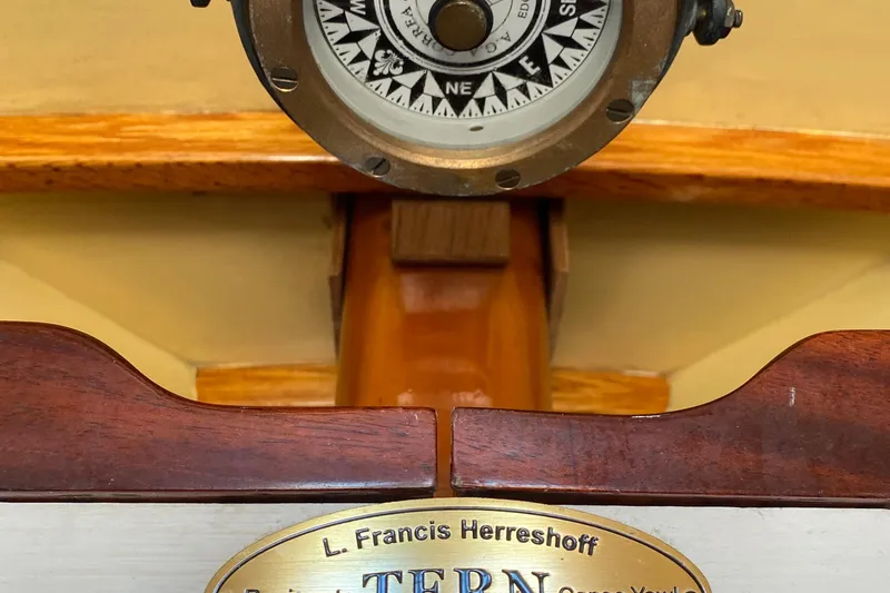 Slide: The Image of Compass and nameplate on 1974 Herreshoff Rozinante sailboat, featuring classic wooden design. - 37