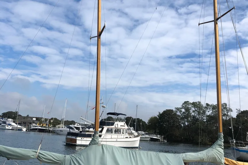 Slide: The Image of Sailboats docked in a marina under a partly cloudy sky, featuring a 1974 Herreshoff Rozinante. - 48