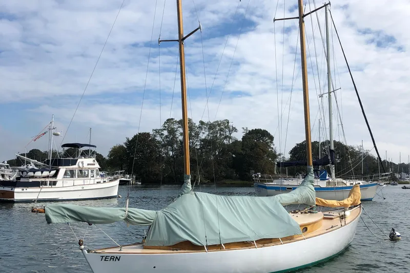 Slide: The Image of 1974 Herreshoff Rozinante sailboat docked in a serene marina setting. - 53