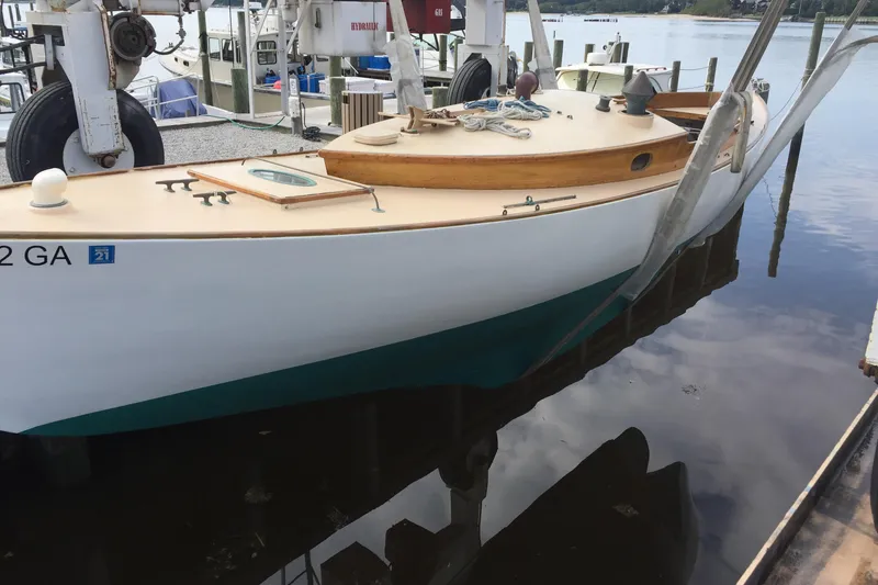 Slide: The Image of 1974 Herreshoff Rozinante sailboat docked at a marina, reflecting on calm water. - 22