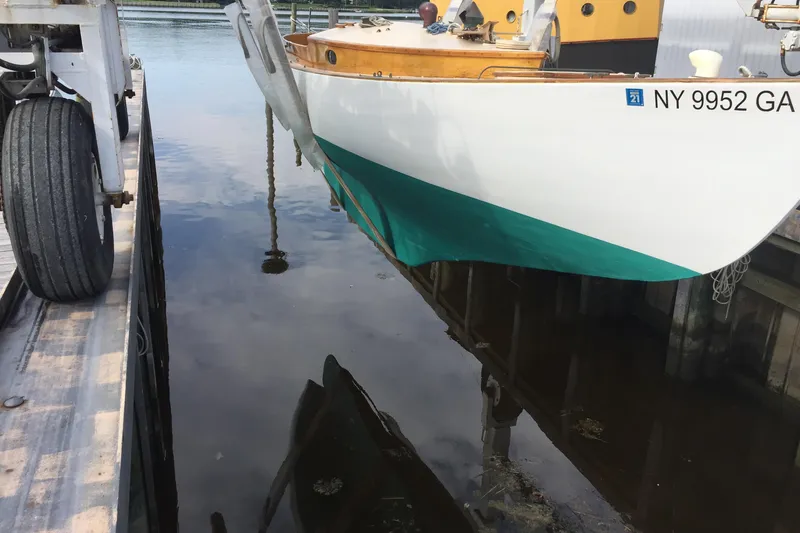Slide: The Image of 1974 Herreshoff Rozinante sailboat docked, partially lifted, with visible registration number. - 21