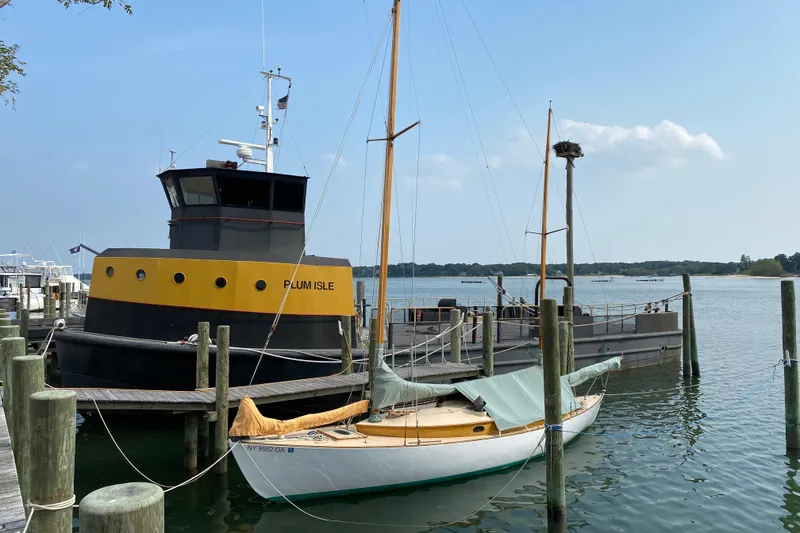 Slide: The Image of 1974 Herreshoff Rozinante sailboat docked beside a large vessel named Plum Isle. - 56