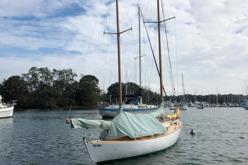 Slide: The Image of 1974 Herreshoff Rozinante sailboat moored in a serene marina setting. - 59
