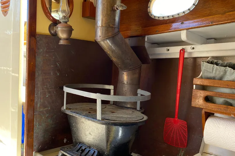 Slide: The Image of 1974 Herreshoff Rozinante interior with vintage stove and nautical decor. - 39