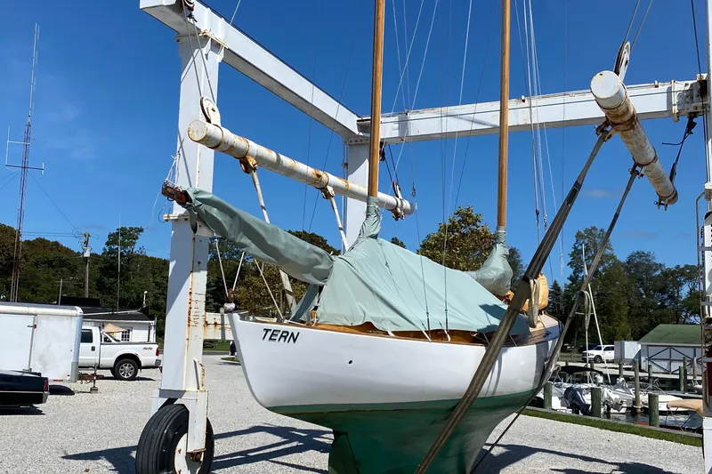 Slide: The Image of 1974 Herreshoff Rozinante sailboat named "Tern" in a boatyard lift under clear blue sky. - 45