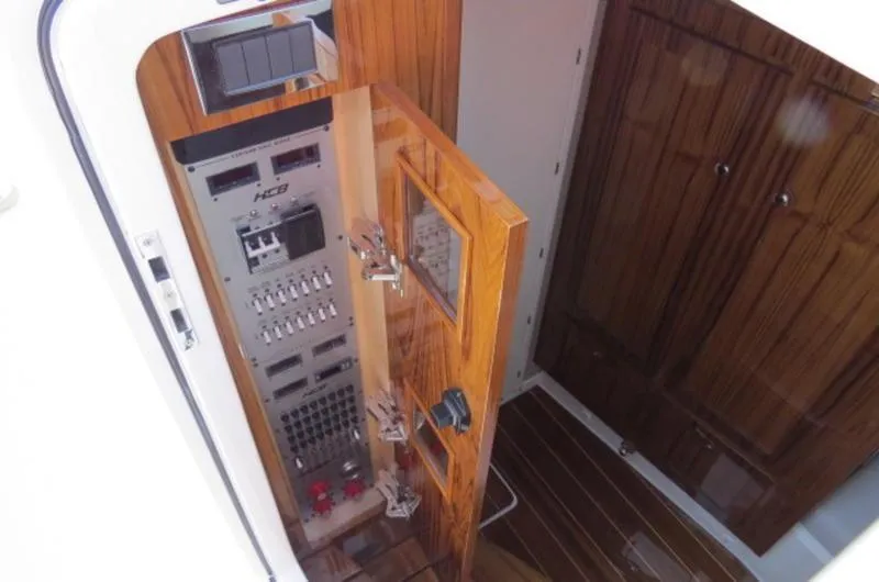 Slide: The Image of Electrical panel inside 2024 HCB 53 FT Suenos boat, featuring wooden cabinetry and modern controls. - 27