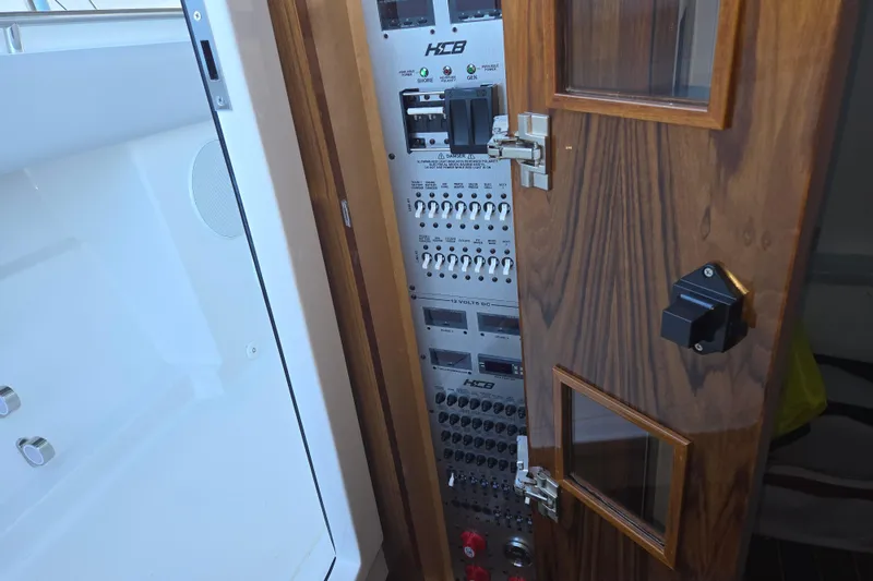 Slide: The Image of Electrical panel inside 2024 HCB 53 FT Suenos yacht, featuring wooden door and control switches. - 35