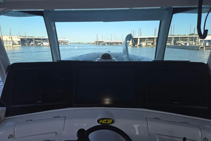 Slide: The Image of 2024 HCB 53 FT Suenos boat cockpit with navigation screens, overlooking marina. - 51