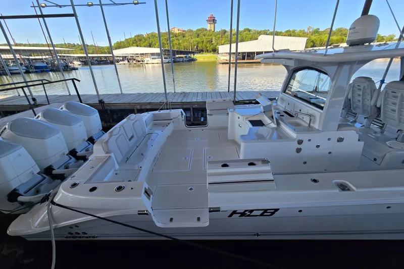 Slide: The Image of 2024 HCB 53 FT Suenos luxury boat docked, featuring spacious seating and multiple engines. - 58