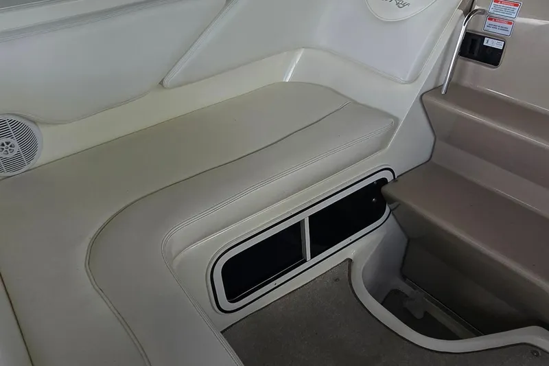 Slide: The Image of 2004 Sea Ray 260 Sundancer interior seating and steps, featuring beige upholstery and storage compartment. - 16