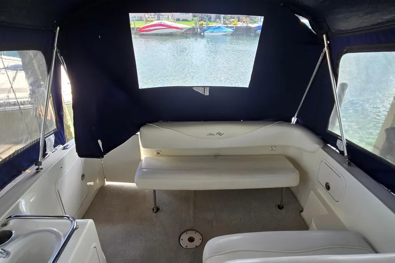 Slide: The Image of Interior of a 2004 Sea Ray 260 Sundancer boat with seating and covered windows. - 17