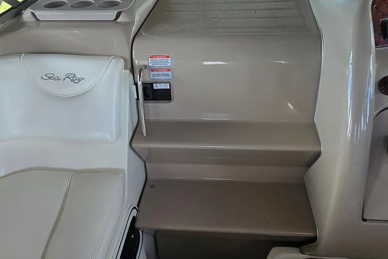 Slide: The Image of 2004 Sea Ray 260 Sundancer interior with seating and steps, featuring cup holders and safety labels. - 18