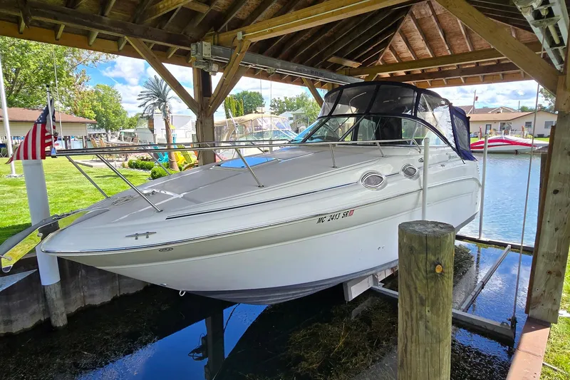 Slide: The Image of 2004 Sea Ray 260 Sundancer boat docked under a wooden shelter by the water. - 2