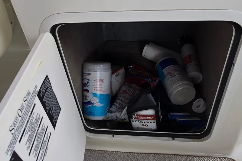 Slide: The Image of Storage compartment on a 2004 Sea Ray 260 Sundancer with cleaning supplies and gear lube. - 21