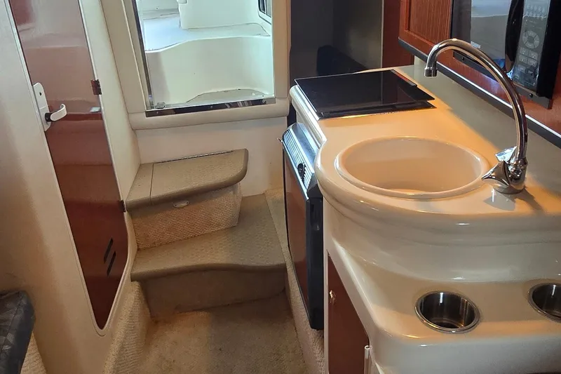 Slide: The Image of Interior of 2004 Sea Ray 260 Sundancer, featuring compact kitchen with sink and stove. - 27