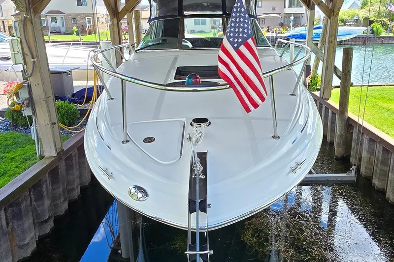 Slide: The Image of 2004 Sea Ray 260 Sundancer docked with American flag, under wooden shelter. - 3