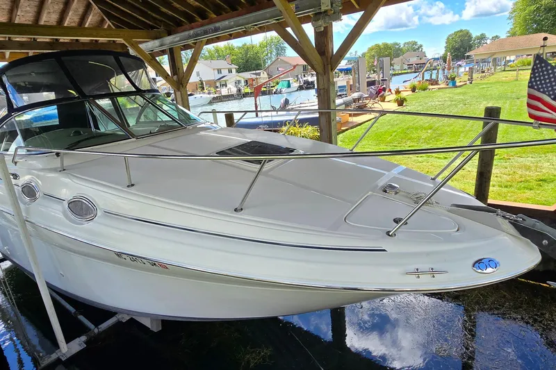 Slide: The Image of 2004 Sea Ray 260 Sundancer docked under a wooden shelter by a scenic waterfront. - 4