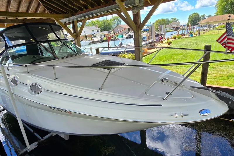 Slide: The Image of 2004 Sea Ray 260 Sundancer docked under a wooden shelter by a scenic waterfront. - 5