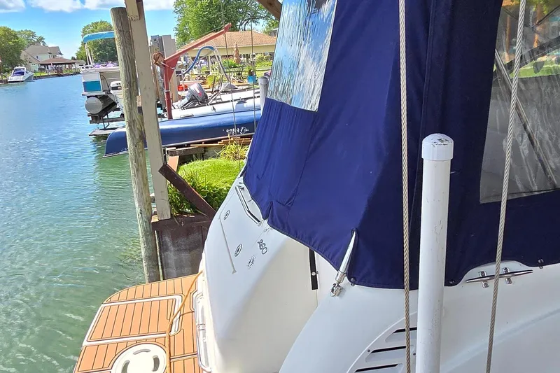 Slide: The Image of 2004 Sea Ray 260 Sundancer docked, featuring blue canopy and wooden deck. - 6