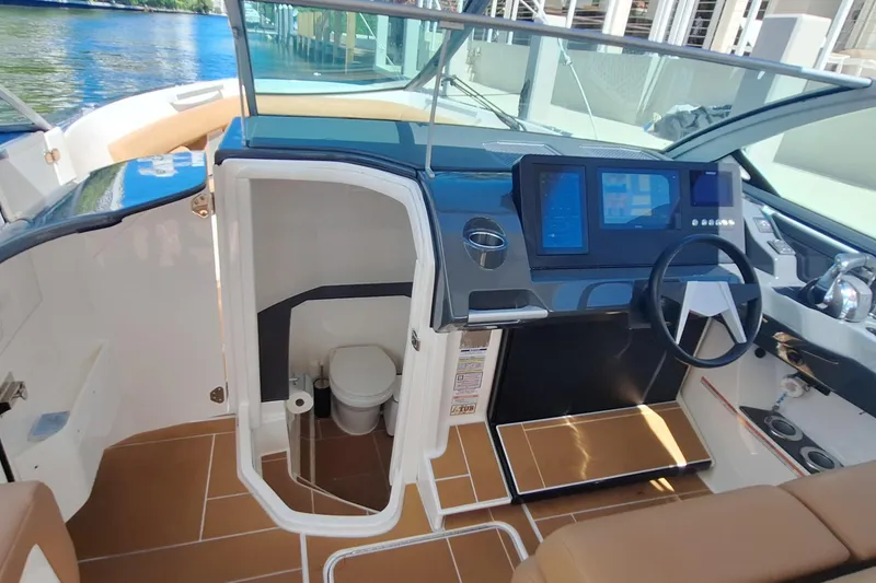 Slide: The Image of 2021 Aviara AV32 OB boat interior with helm, digital displays, and compact restroom. - 22