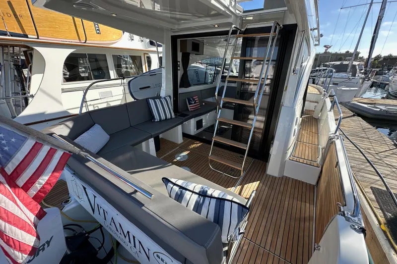 Slide: The Image of 2023 Beneteau Antares 11 Fly yacht with elegant seating and American flag, docked at marina. - 11