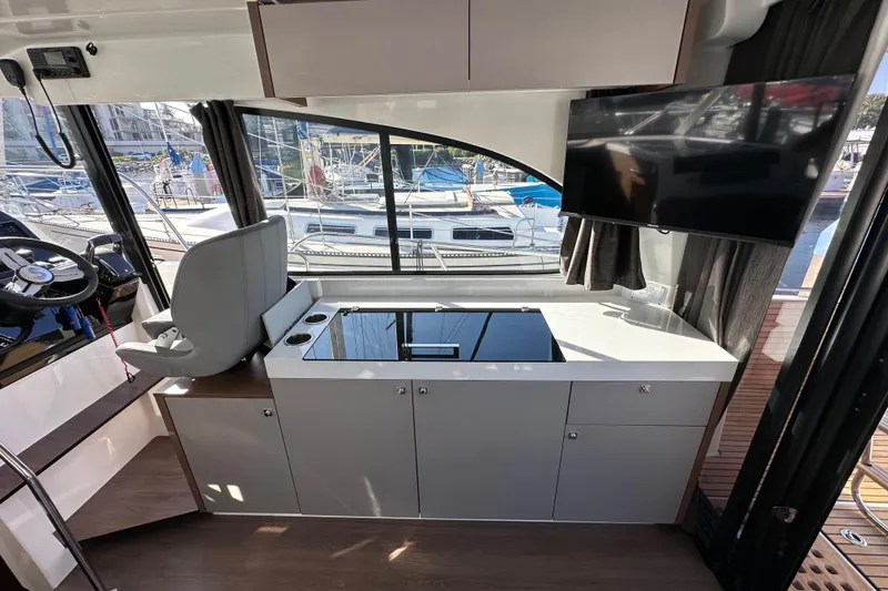 Slide: The Image of Interior of 2023 Beneteau Antares 11 Fly, featuring helm, kitchenette, and marina view. - 34