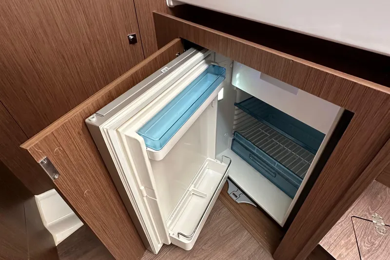 Slide: The Image of 2023 Beneteau Antares 11 Fly interior fridge with open door, showcasing storage space. - 53