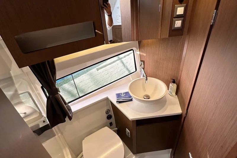Slide: The Image of 2023 Beneteau Antares 11 Fly bathroom with modern sink, window, and wooden cabinetry. - 58
