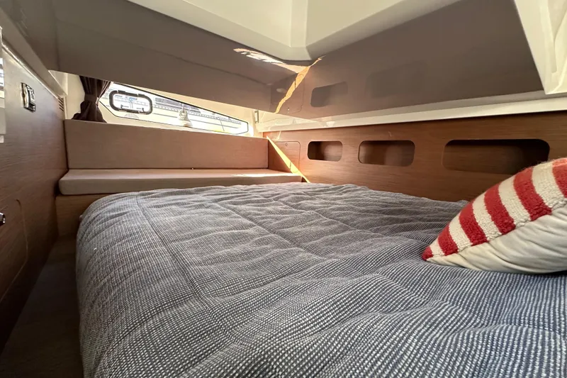 Slide: The Image of 2023 Beneteau Antares 11 Fly cabin interior with cozy bed and striped pillow. - 95