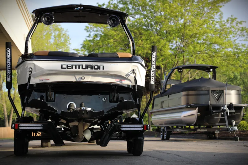 Slide: The Image of 2025 Centurion Nv213 boat on trailer, parked outdoors with trees in background. - 22
