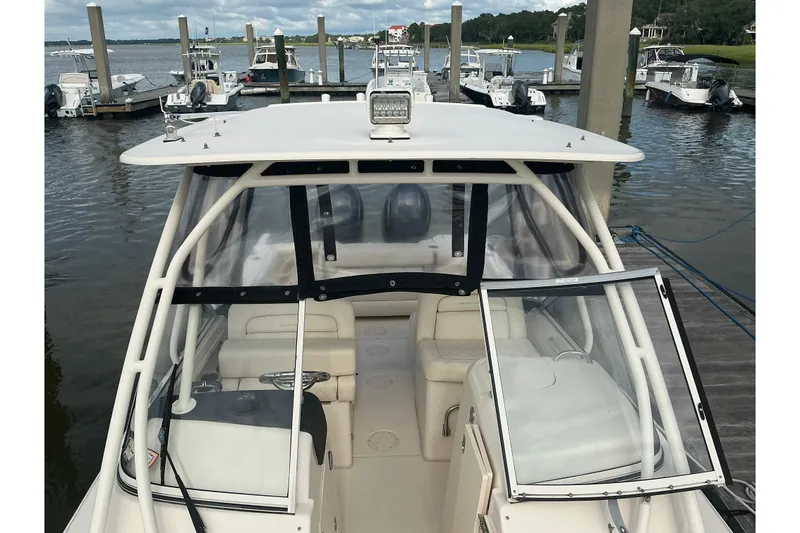 Slide: The Image of 2020 Grady-White Freedom 225 boat docked at marina, featuring spacious seating and clear enclosure. - 3
