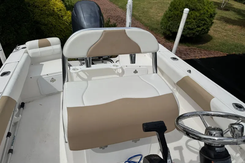 Slide: The Image of 2019 Edgewater 188CC boat interior with beige and white seating, steering wheel, and motor. - 14