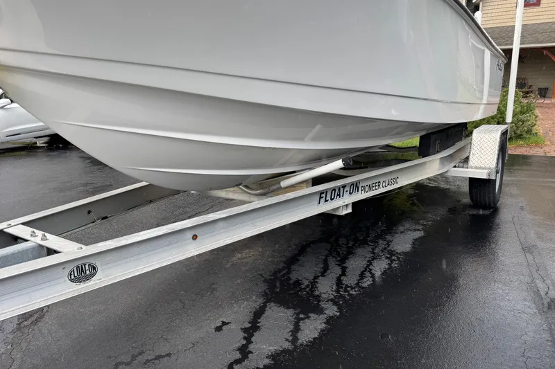 Slide: The Image of 2019 Edgewater 188CC boat on a Float-On Pioneer Classic trailer, parked on wet pavement. - 19