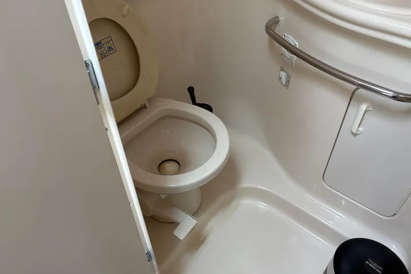 Slide: The Image of Toilet area in 2001 Sea Ray 340 Sundancer boat, featuring compact design and safety rail. - 13