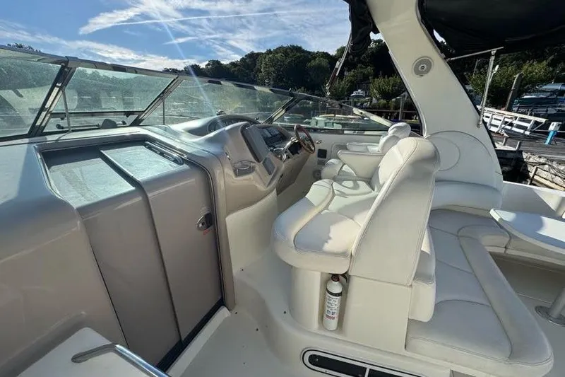 Slide: The Image of 2001 Sea Ray 380 Sundancer cockpit with white seating and control panel, docked under clear skies. - 10