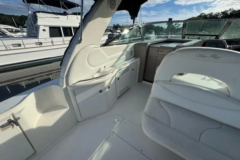 Slide: The Image of 2001 Sea Ray 380 Sundancer cockpit with white seating and cabinetry, docked at marina. - 12