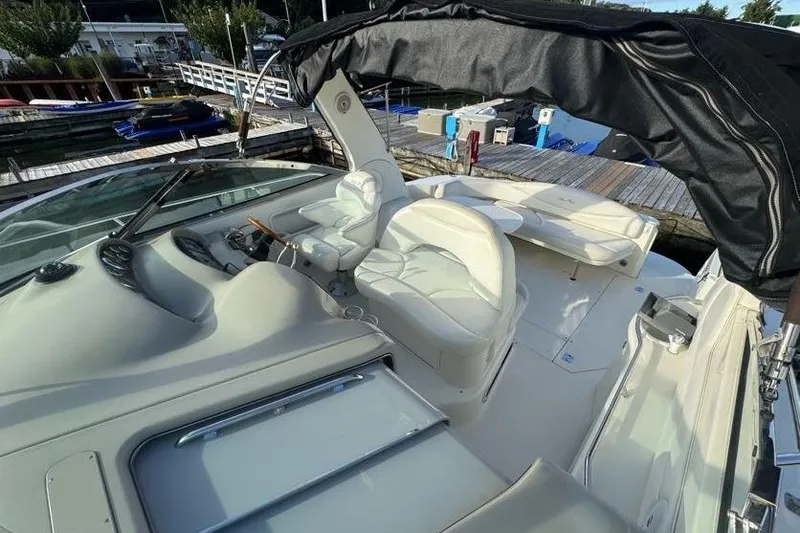Slide: The Image of 2001 Sea Ray 380 Sundancer boat interior with white seating and helm, docked at marina. - 16