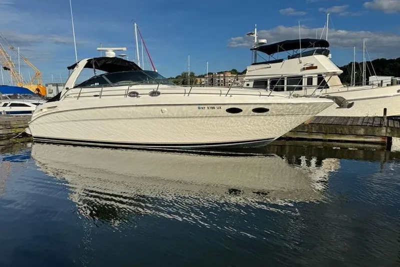 Slide: The Image of 2001 Sea Ray 380 Sundancer yacht docked in a marina, reflecting on calm water. - 2